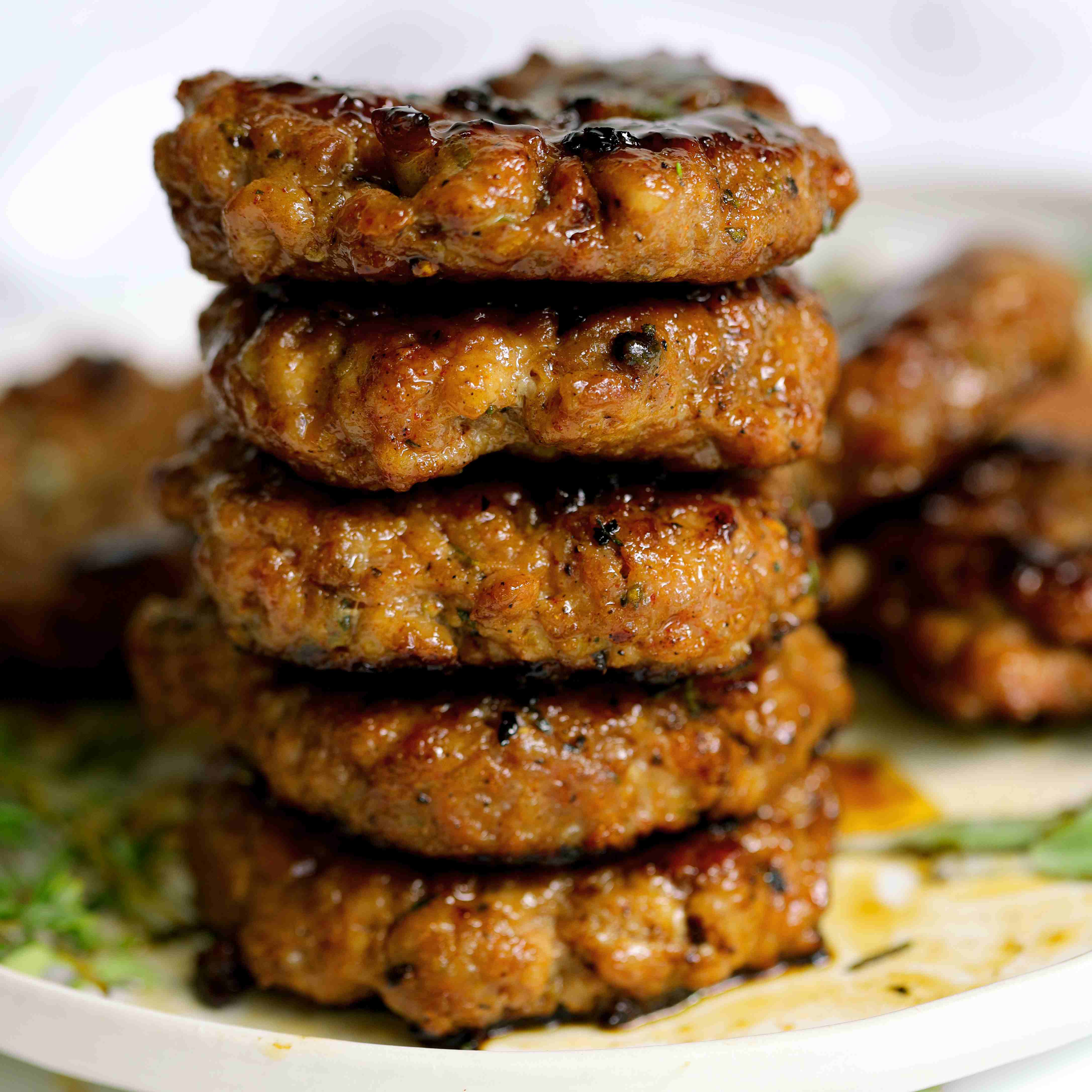 Stack of prepared Breakfast Sausage Recipe on a white plate with fresh thyme