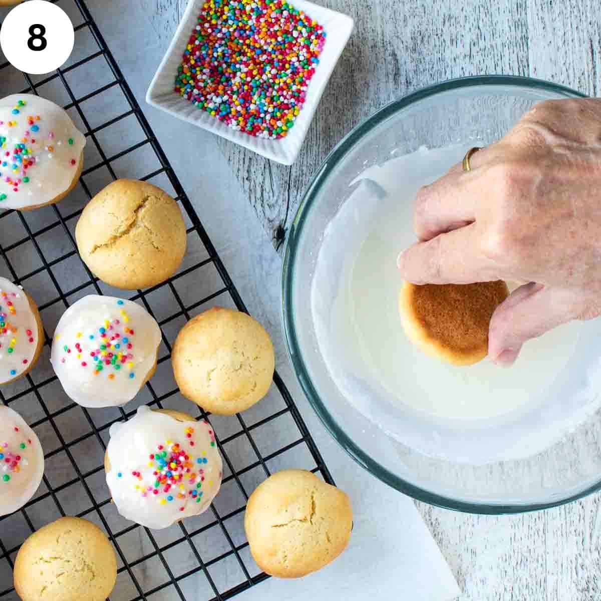 Hands dipping cookies into icing.